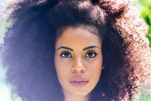 Portrait of nice afro girl in a garden. Close up. Selective focus.