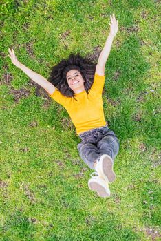 Pretty afro woman lying on her back in a garden. Aerial view. Selective focus.