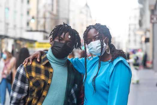 Black couple in the city. With masks. Selective focus.