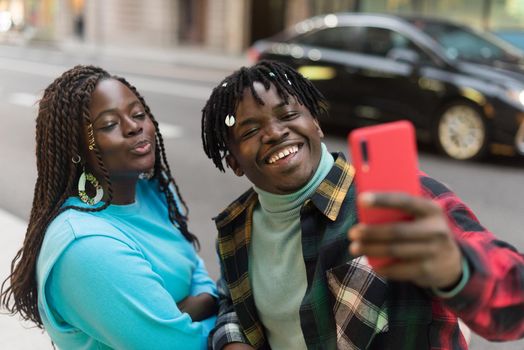 Smiling black couple taking a selfie on the street. Selective focus.