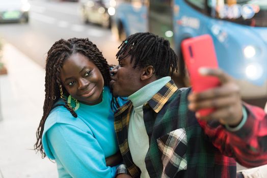 Smiling black couple taking a selfie on the street. Selective focus.