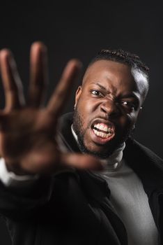 Very angry black man telling you to stop with an open hand, fighting for his rights. Close up. Black background.