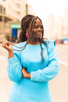 Pretty young black woman smiling in the middle of the city. Selective focus.