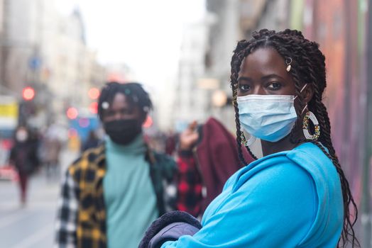 Black couple in the city. With masks. Selective focus.