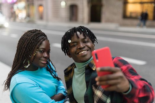 Smiling black couple taking a selfie on the street. Selective focus.