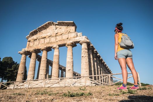 Woman contemplating a temple at the greco-roman archaeological site of Paestum, Italy.