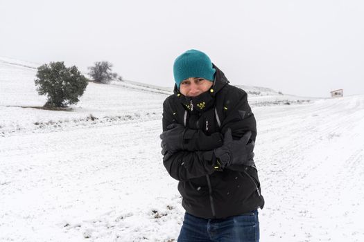 Very cold man with coat, hat and gloves, in the middle of a snowfall. Spain.