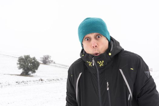 Very cold man with coat, hat and gloves, in the middle of a snowfall. Spain.