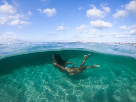 Woman diving into the sea. View at water level, photo with underwater dome.