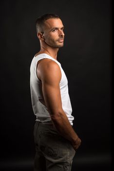 Athletic man in casual clothes. Mid shot. Black background.