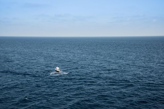 Small boat in the middle of a huge sea on a sunny summer day.