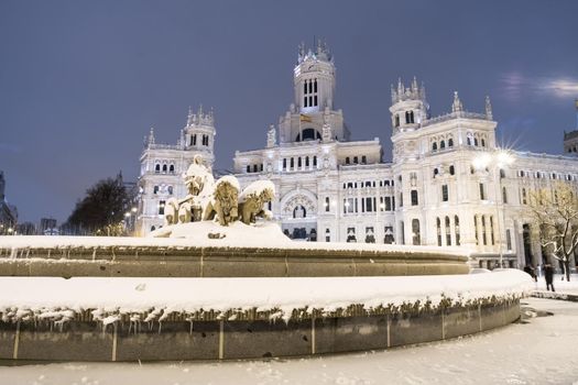 Plaza de la Cibeles in Madrid on a cold winter night after a heavy snowfall.