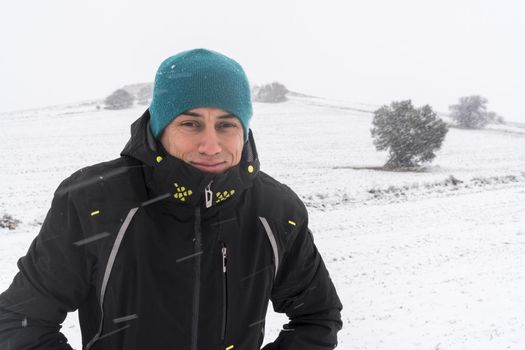 Smiling man with coat and hat, in the middle of a snowfall. Spain.