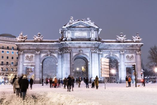 Puerta de Alcala in Madrid on a cold winter night after a heavy snowfall.