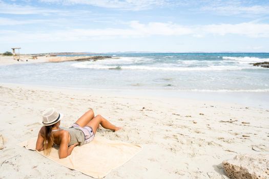 Pretty woman sunbathing on the beach. Long shot. Formentera island, Spain.