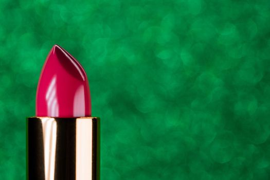Pink lipstick rising out from container on shiny green background. Showcase or advertisement for beauty brand, Concept of fashion, cosmetics with copy space. High quality
