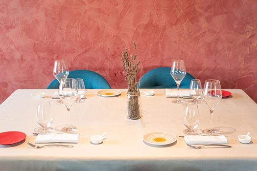 Front view of various glasses and cutlery ready to use in a hotel dining room. Concept of hotel.