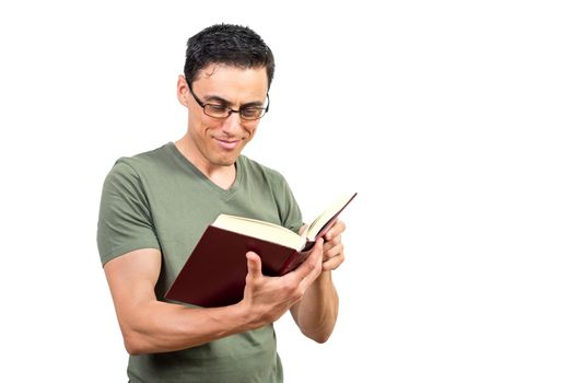 Positive smart male in glasses reading interesting story in book against white isolated background