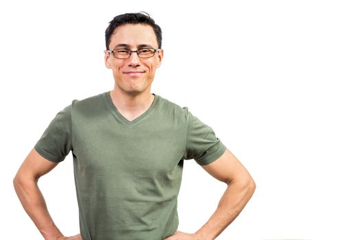 Glad clever man in green t shirt and glasses holding hands on waist and looking at camera with smile against white background