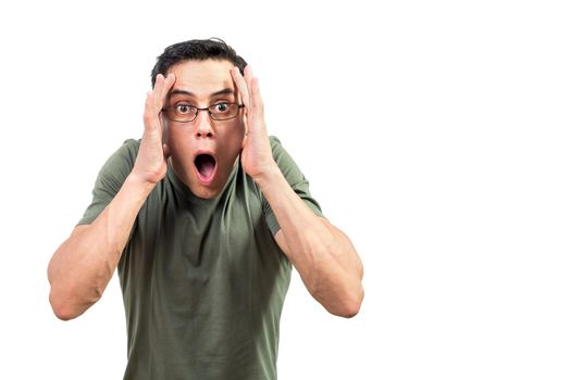 Astonished man in green t shirt and glasses touching head and looking at camera with opened mouth against white background