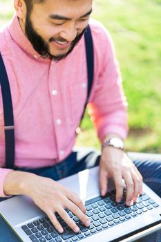 Top view and cropped photo of an asian man working with a laptop in a park