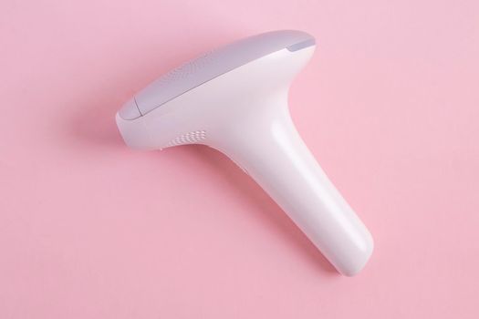home modern laser epilator. Hair Remover offering Permanently Smooth Skin. Flash Epilator Laser on a pink background. Female blog concept. Photoepilator for home use. High quality photo