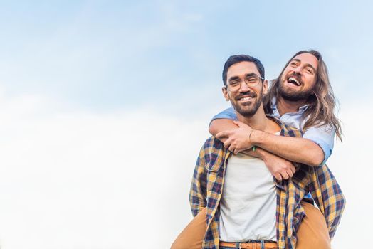 Front view of a young man looking at the camera while carrying his partner on his back with copy space.