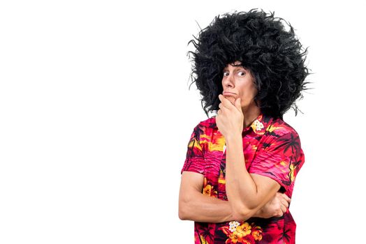 Pensive man in vivid shirt and funny Afro wig touching chin and thinking against white background