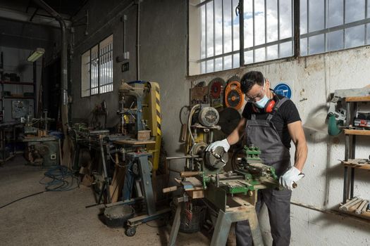 Worker standing with mask and protective equipment in a factory. Mid shot.