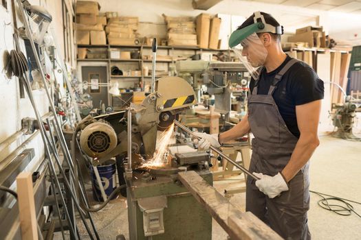 Man with protective equipment working on a machine in a factory. Mid shot.