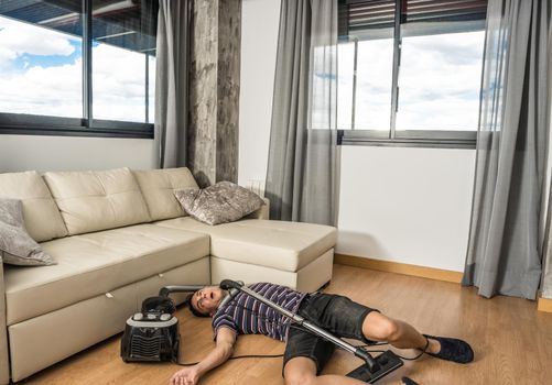 Man desperately trying to understand how a vacuum cleaner works to vacuum the living room. Full body.