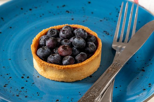 Freshly baked blueberry tart on a blue porcelain plate