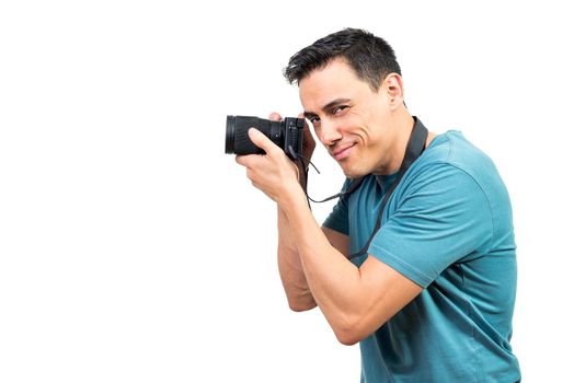 Side view of sly male photographer taking photo on professional photo camera on white isolated background
