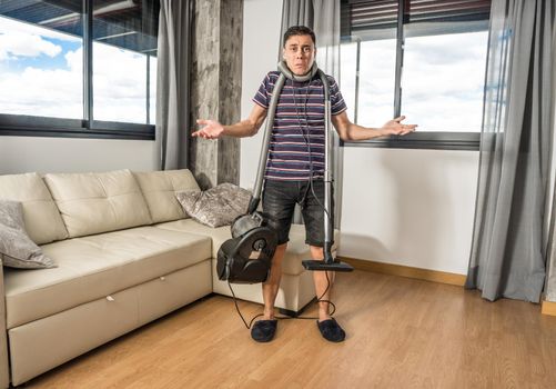 Man desperately trying to understand how a vacuum cleaner works to vacuum the living room. Full body.