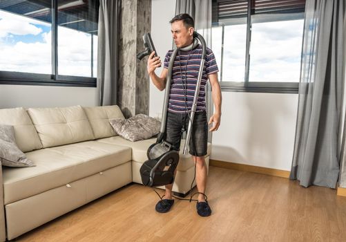 Man desperately trying to understand how a vacuum cleaner works to vacuum the living room. Full body.