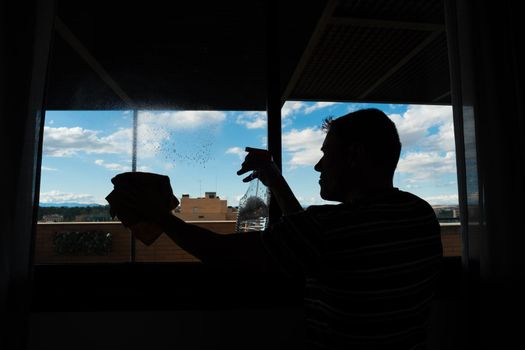 Man cleaning the windows at home. Full body.