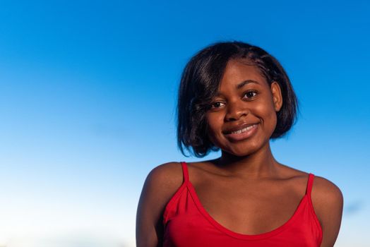 Close up portrait of a young african woman smiling while facing the camera during sunset