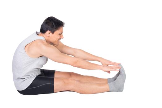 Full body side view of sportive male in activewear with socks stretching femoral muscle isolated on white background in studio