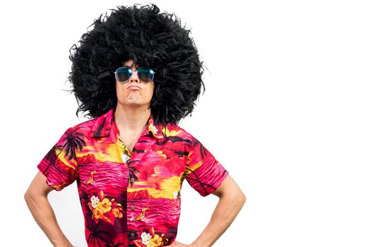 Self assured male in colorful shirt with stylish sunglasses and funny Afro wig holding hands on waist and pouting lips against white background