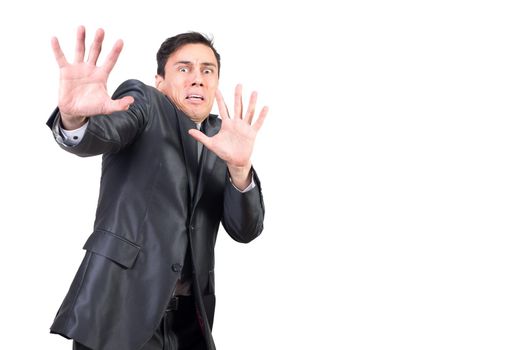 Scared young male employee with dark hair in formal suit gesturing no at camera and looking with horror on face isolated on white background