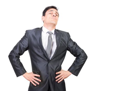 Self assured young male boss with dark hair in formal suit and tie standing against white background with hands on waist and looking at camera with confidence