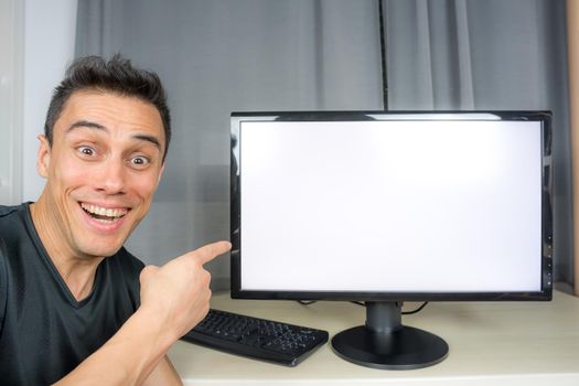 Smiling man in black shirt pointing at a computer screen announcing important news. Close up.