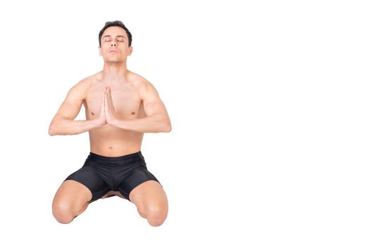 Full body of peaceful muscular male with naked torso sitting isolated on white background with closed eyes and namaste gesture