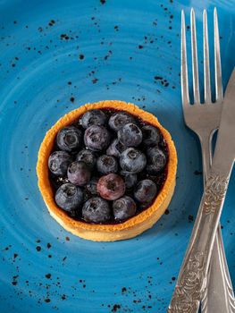 Freshly baked blueberry tart on a blue porcelain plate