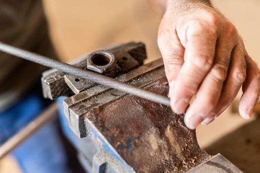 close-up of a hand filing metal, horizontal