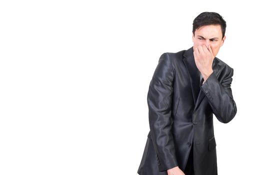 Disgusted male in formal suit pinching nose and looking away while feeling bad smell isolated on white background in light studio