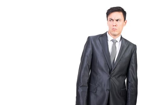 Distrustful male manager in formal suit standing against white background and looking away with puzzled look
