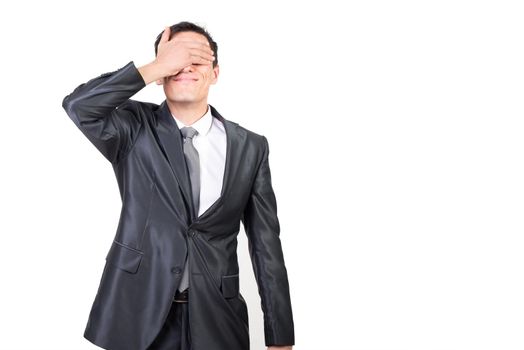 Confident surprised male in formal suit covering eye with hand while standing on white background