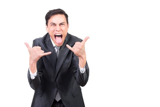 Cheerful adult male with open mouth and tongue out showing rock gesture while standing against white background and looking at camera
