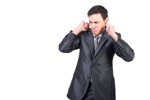 Frustrated young male manager in classy suit covering ears with fingers while standing on white background